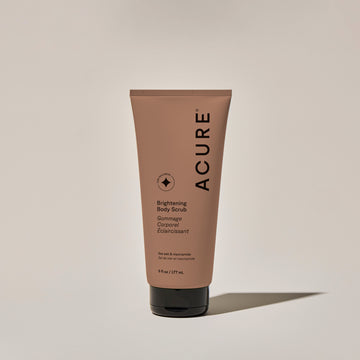 A tube of ACURE Brightening Body Scrub against a neutral background.